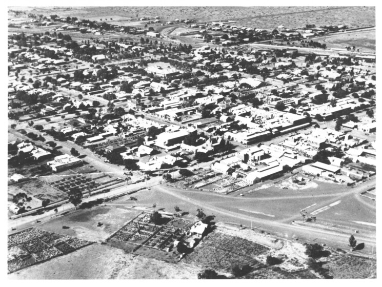 Black and white aerial photograph of a country town, the dry streets and surrounding paddocks all dirt.