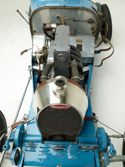 A close up view of the cars motor. The bonnet has been removed so you can see all of bolts, pipes and levers.