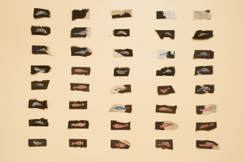 A selection of individual art pieces pinned to a wall, rather small in size and symmetrical in their positioning.