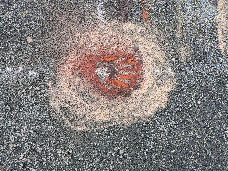 Close up view of sand patterns on the bitumen road, made up on red and yellow circles.