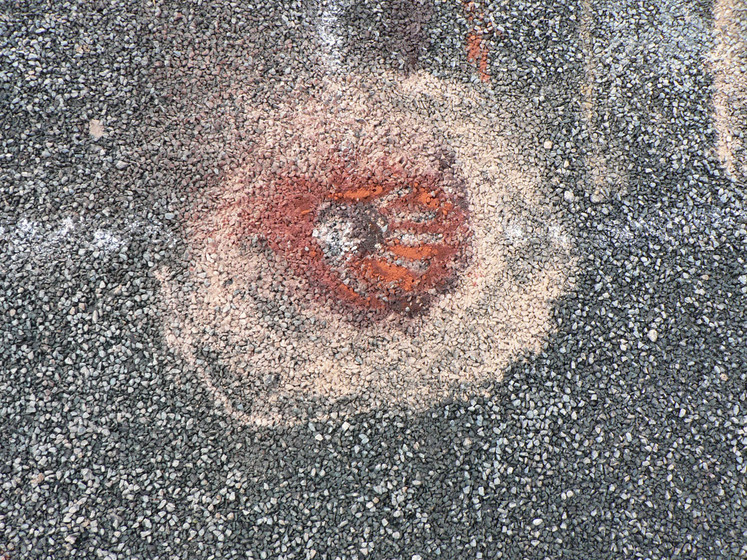 Close up view of sand patterns on the bitumen road, made up on red and yellow circles.