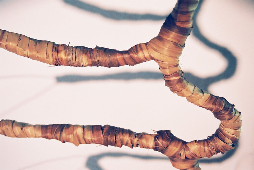 Curved wire wrapped in a type of rattan, reflecting the look of a tree branch.