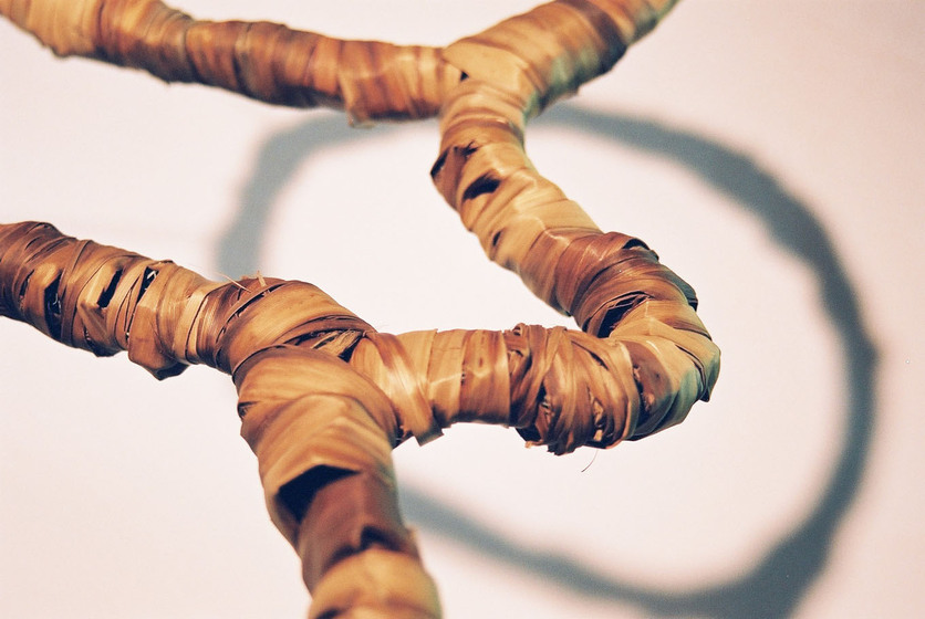 Curved wire wrapped in a type of rattan, reflecting the look of a tree branch.