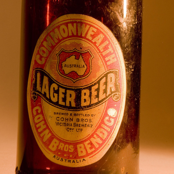 Brown bottle with an oval label on the front, spelling out the name of the bottle and where it is made in red, black and white colours.