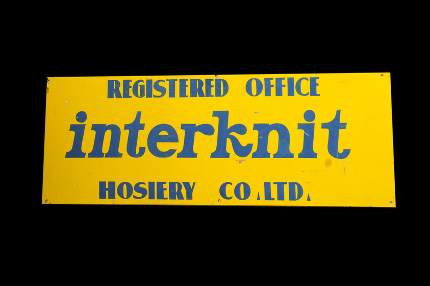 A yellow sign which says 'registered office interknit hosiery co ltd'