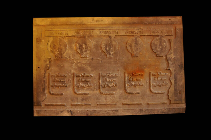 A rubber stamp with a series of different symbols and lettering embossed on the base.