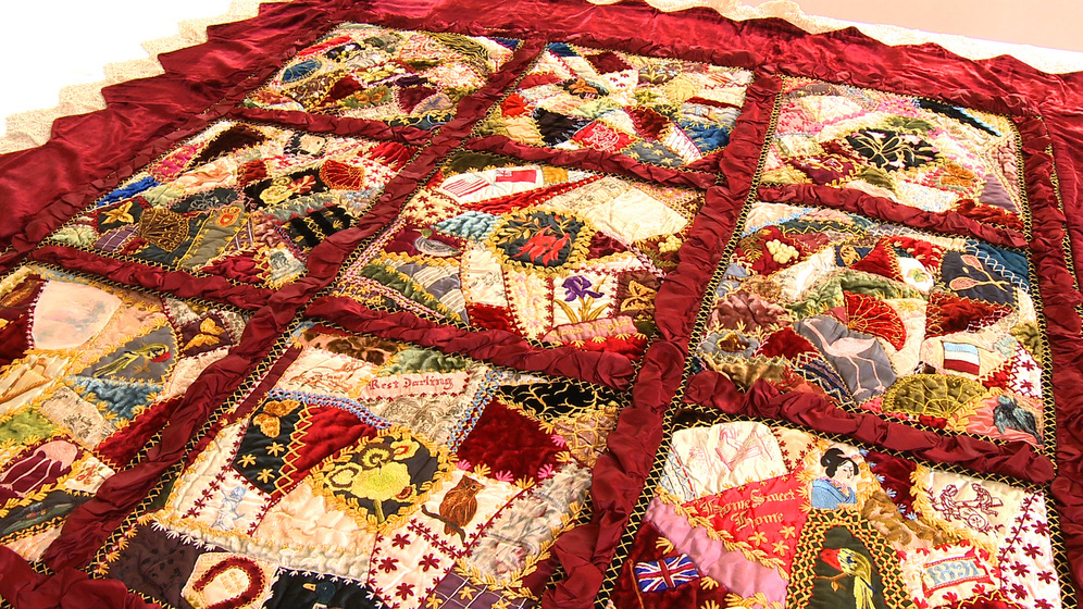 A colourful patchwork quilt made up of 9 panels, each with a selection of embroidered designs and fabric patches.