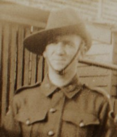 A man wearing a military jacket and Australian army slouch hat, view of torso only.