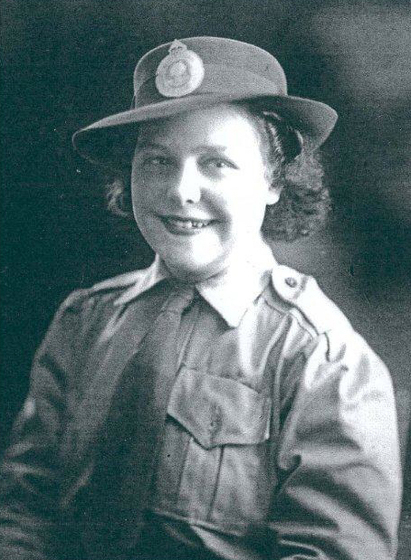 Studio torso portrait of a young woman in military uniform and hat.