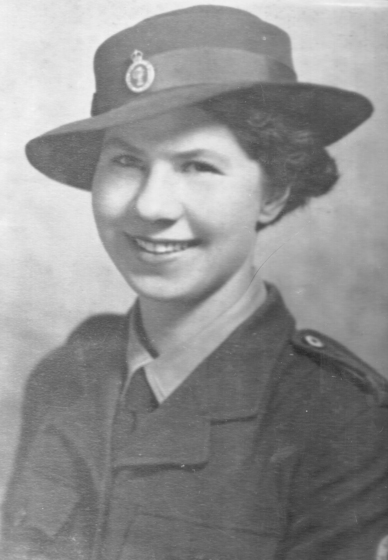 Studio torso portait of a young woman in military uniform and hat.