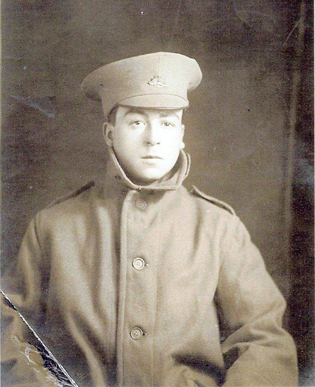 Studio torso portrait of a young man in a large military coat and hat.