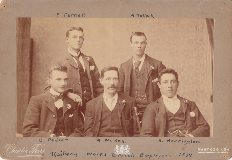 Studio group portrait  mounted on card to form a. Image shows five men in suits, three seated in front, two standing behind. Handwritten text above the image reads 'E.Furnell, A. Tulloch'. Handwritten text below the image reads 'C. Pedler, A. McKay, H. Harrington. Railwork Works Branch Employees 1899.