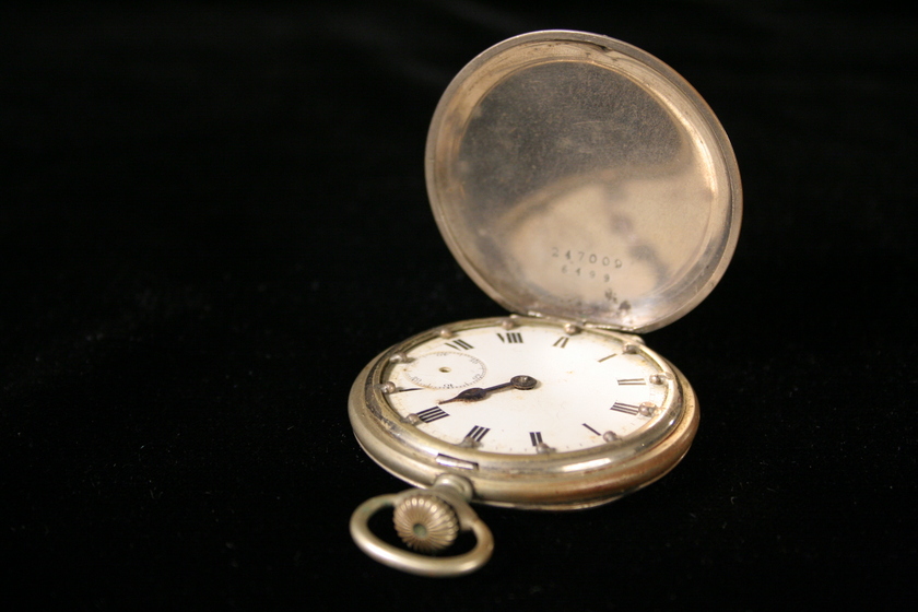 An open silver fob watch with roman numerals on the face.