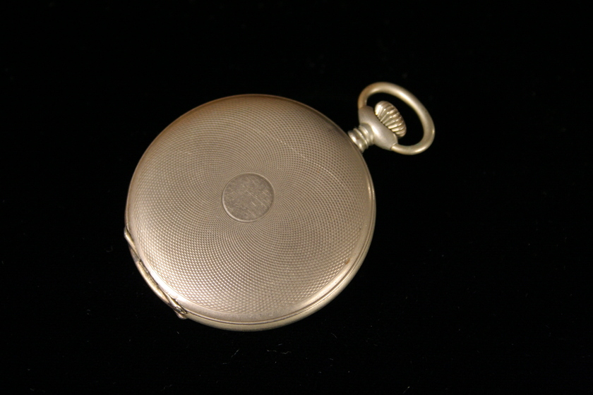 Closed silver fob watch with light dotted patterning on the surface