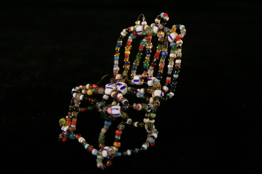 Side view of a small chair made from white multi-coloured small beads.