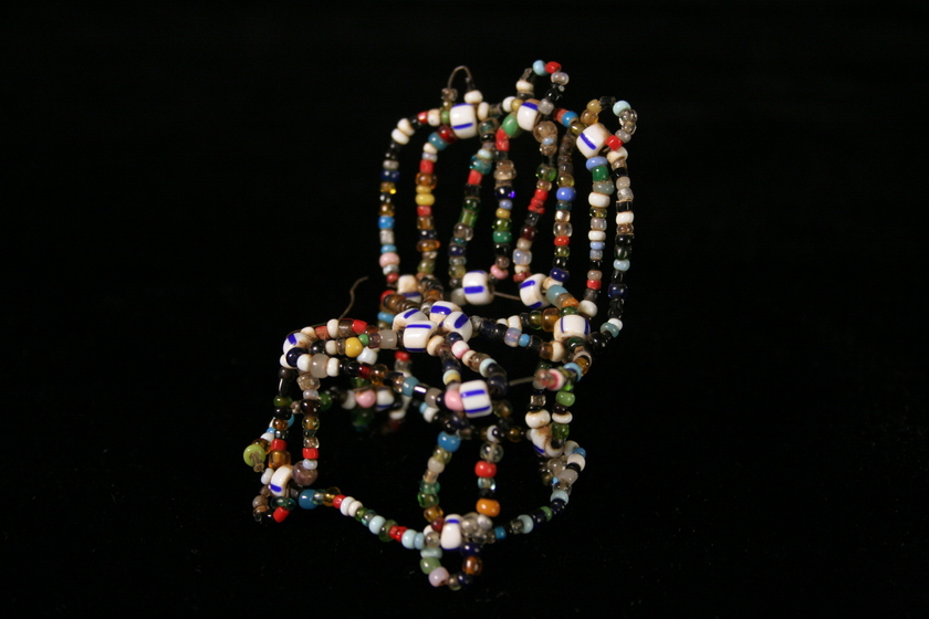 Side view of a small chair made from white multi-coloured small beads.