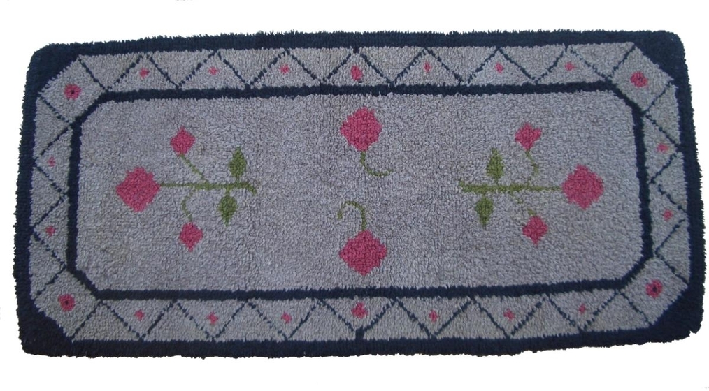 Grey wool rug with rose detail pattern and black pattern border edging.