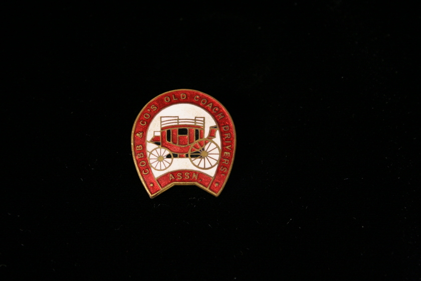 Enamel badge with red border and red carriage on a white background.