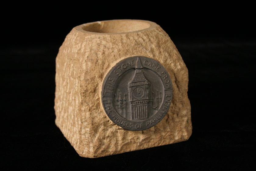 Textured Stone with a concave smooth section carved into the top, with a bronze circular plaque showing a clock tower on the face. 