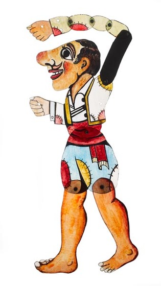 Acrylic figure of a man, jointed with pins at the waist, knees, and multiple sections along one arm. He has an exaggerated face with large nose, and wears patchwork shorts and a white vest. 