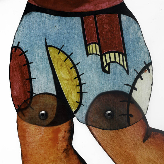 Close up view of a pair of shorts on am acrylic figure, with pins holding legs seen. The shorts are blue, with red, yellow and white patches. 