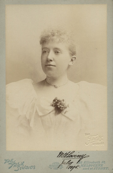Studio torso portrait of a young woman wearing pearls and a white dress. 