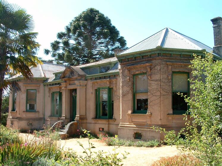 Ornate one story building with vines growing along the walls. Steps feature up to a door, and there are windows all around.
