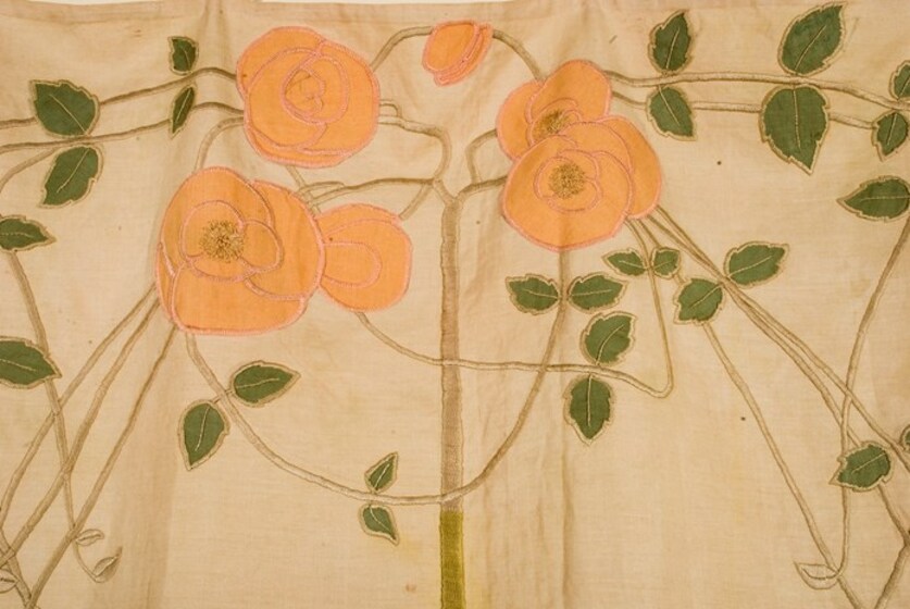 Fabric embroidered with red flowers and small green leaves and vines.
