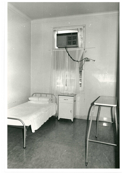 A bedroom at Mont Park, which includes a single bed, an air conditioner, a side table and a moving shelf.