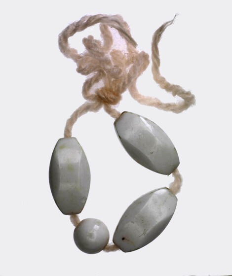 Pink wool tied in a circle, with three large oblong grey beads, and one small circular bead strung on.
