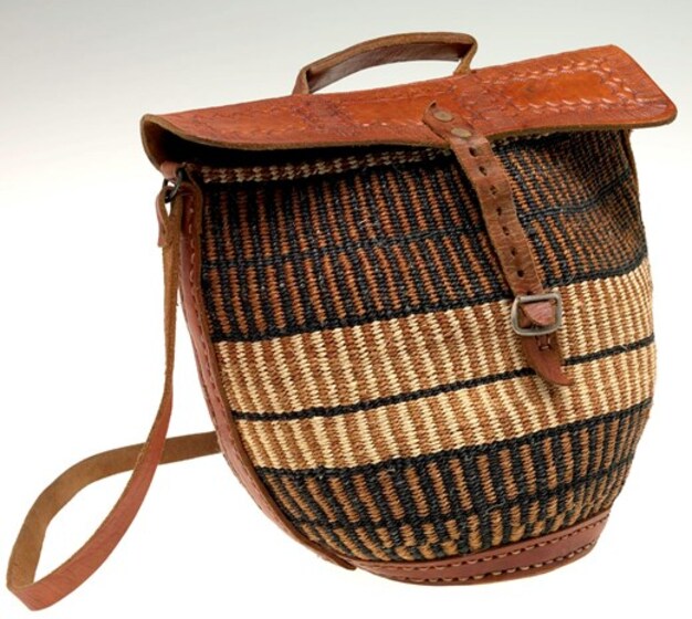Woven light and dark brown, and black striped reed bag with leather handle, flap and clasp.