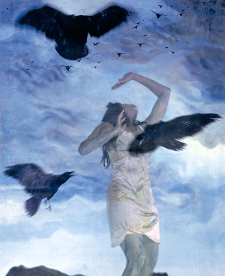 Painting featuring a young woman in a white slip dress, looking up to the sky with one arm raised, with three black birds flying around, and in the distance above many smaller black birds.