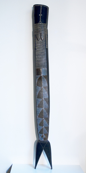 Tall black, brown and white cylindrical sculpture standing on two fins, and decorated in line patterning