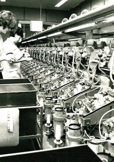 Room with a row of identical machines, with two women standing in front of.