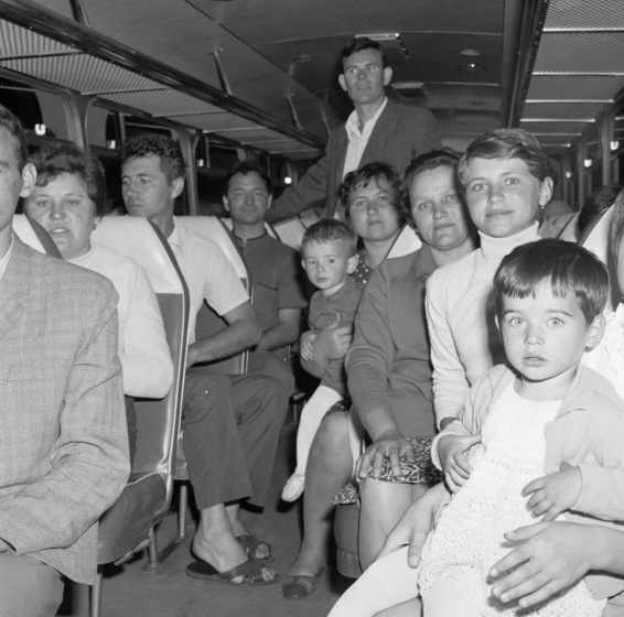 Interior of a bus, showing a group of people, including two children, seated and standing inside.