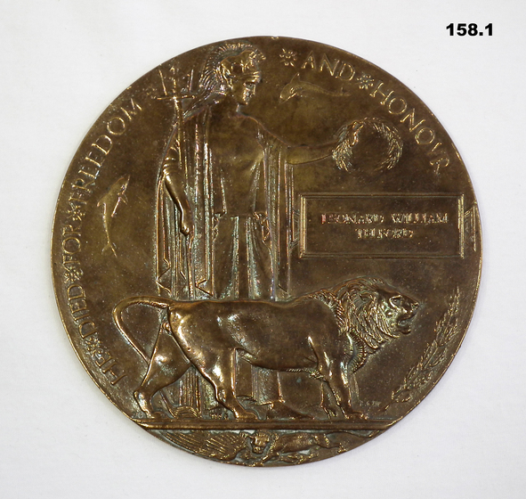 Brass medallion with image of a standing figure 'Lady Britannia' holding a laurel wreath, a dolphin on either side, and a standing lion in front. Words "Freedom and Honour" around top, "Leonard William Telford" in box on right.