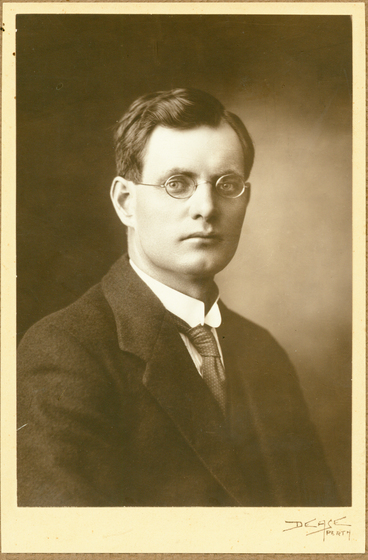 Man in suit and tie wearing circular rimmed glasses