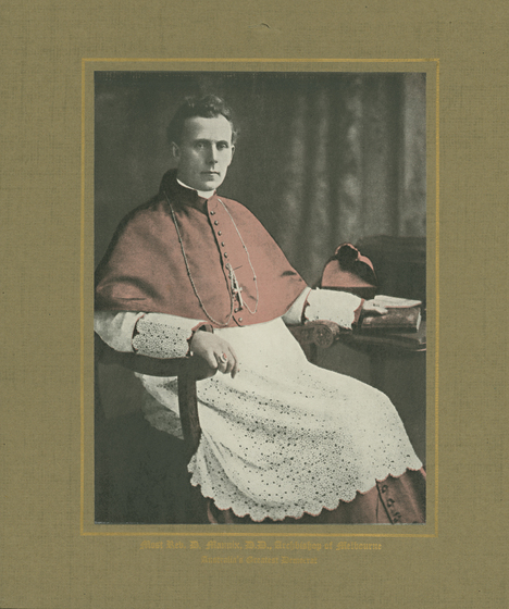 Tinted photograph of man in clerical attire seated in an armchair.