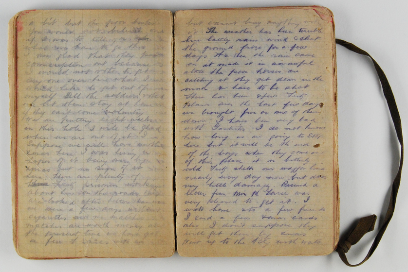 Handwritten diary open to two pages closely filled with text, strap to bind diary visible on right.