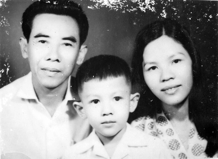 Young man in a white shirt, young woman in a dot print top, with a young boy in a white shirt between them.