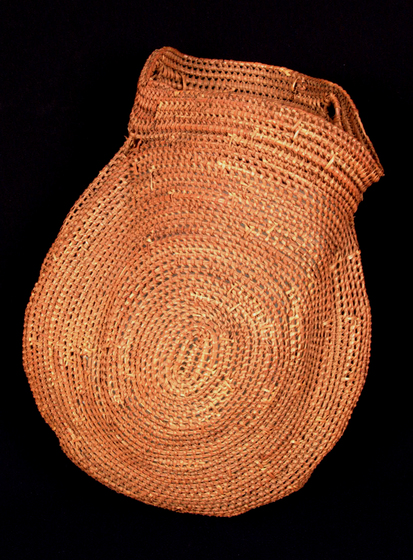 Basket with a narrow opening made from woven reed or plant material, in a circular pattern.