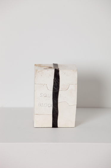 White box sitting on a white surface, with a black band wrapped over the top and front side. 