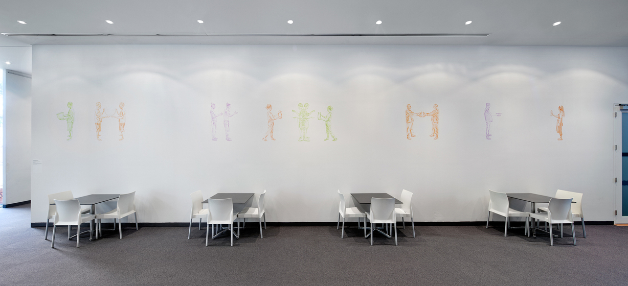 A white wall featuring a series of line drawn coloured people in lime green, orange and purple. In front of the wall on carpeted floor are four tables each with three white chairs. 