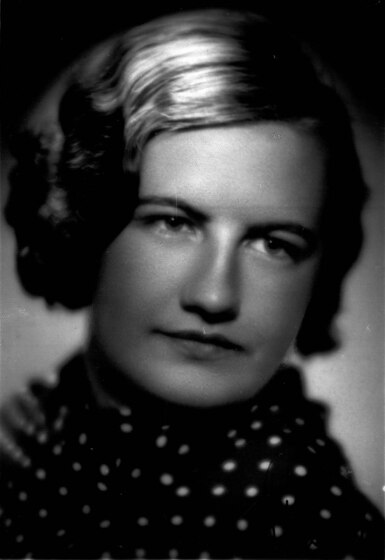 Black and white headshot studio portrait of a woman with short hair, and a black scarf with white dots around her neck.