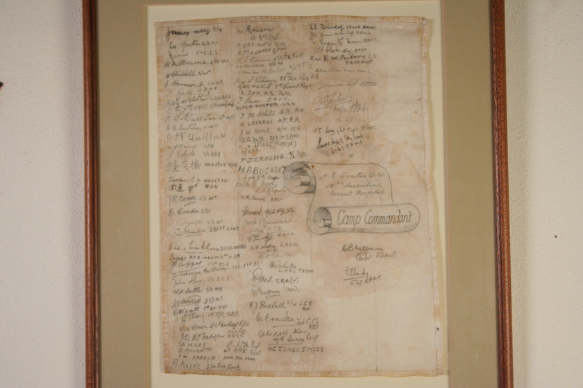 Paper that is yellow and brown with age, with three columns of handwritten names, framed in a thin timber frame.