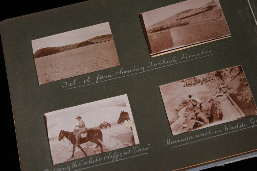 Page from a photo album containing four black and white photographs stuck on an olive green background, with white text beneath each. The photographs are of landscapes, and a person riding a horse.