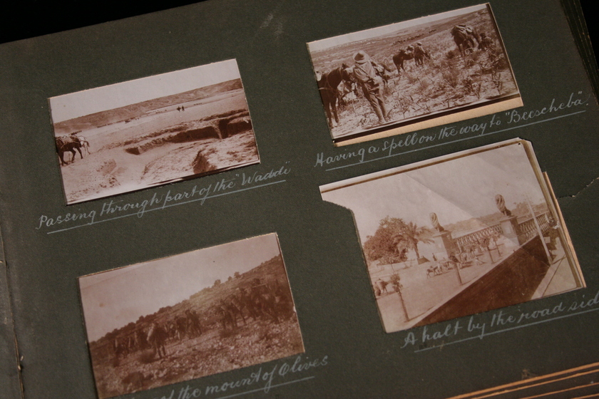 Page from a photo album containing four black and white photographs stuck on an olive green background, with white text beneath each. The photographs are of landscapes, and a people riding horses