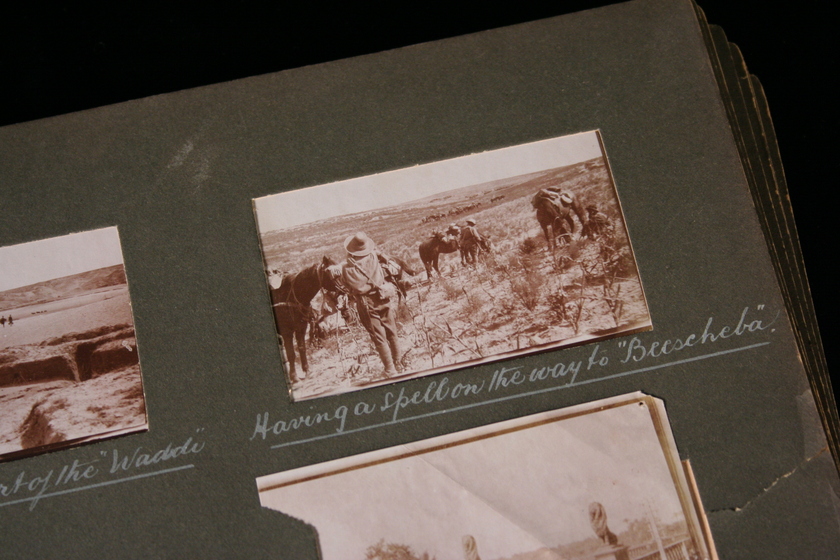 Close up of a page from a photo album, with three black and white photographs visible, and white handwritten text below. The focus photograph shows people riding horses in a landscape. 