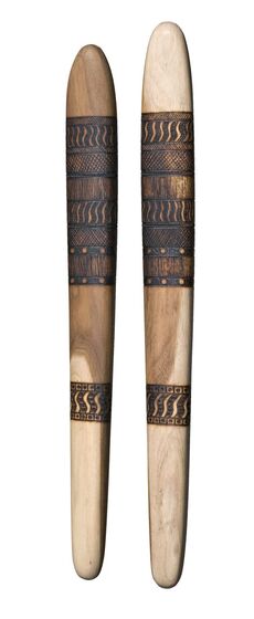 Two carved and flattened wooden sticks with curved ends. Each stick has a lined pattern made from burning the timber.