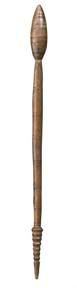 Long thin club made from light coloured wood, with a carved ring pattern coming to a point at the bottom, and an oval bulb shape carved at the top. There are some small line and dot markings along the surface.